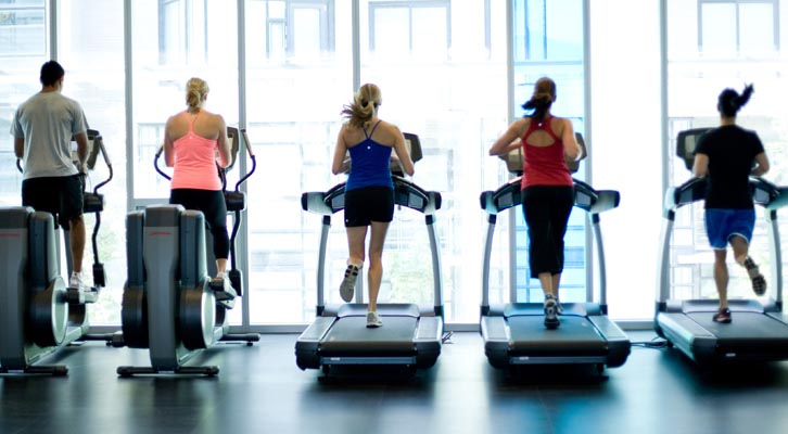 People on treadmills and elliptical machines in a gym