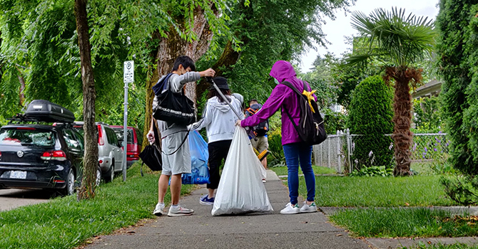 Volunteers place litter into a trash bag in a residential neighbourhood Volunteers place litter into a trash bag in a residential neighbourhood