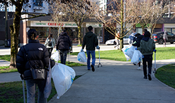 Volunteers collecting litter in trash bags along a city street. Volunteers collecting litter in trash bags along a city street.