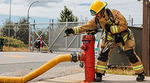 A firefighter unscrews a fire hydrant A firefighter unscrews a fire hydrant