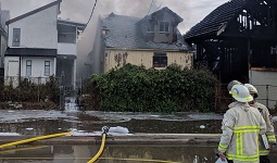 A firefighter standing in front of a burnt house A firefighter standing in front of a burnt house